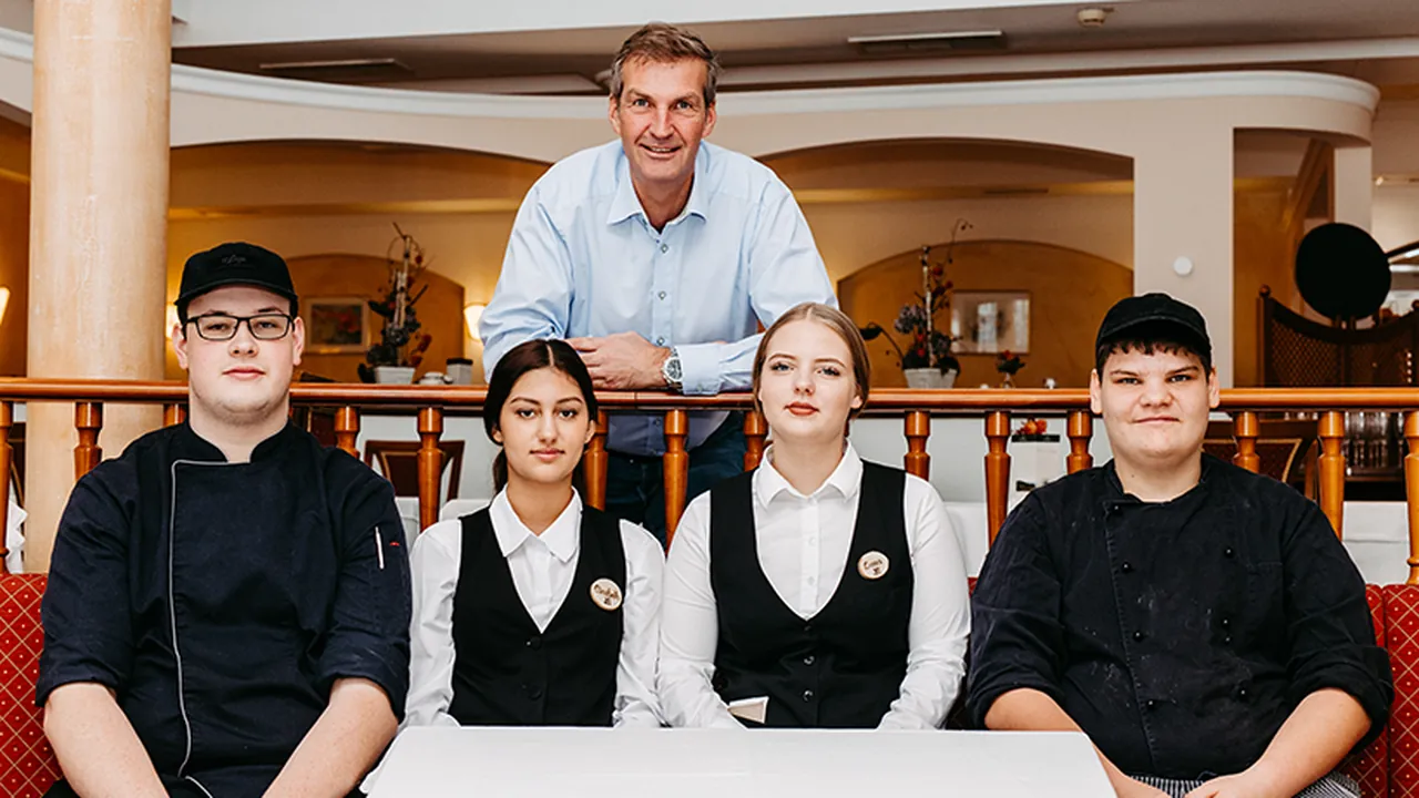 Gruppe junger Menschen in Gastronomieberufen mit ihrem Ausbildner